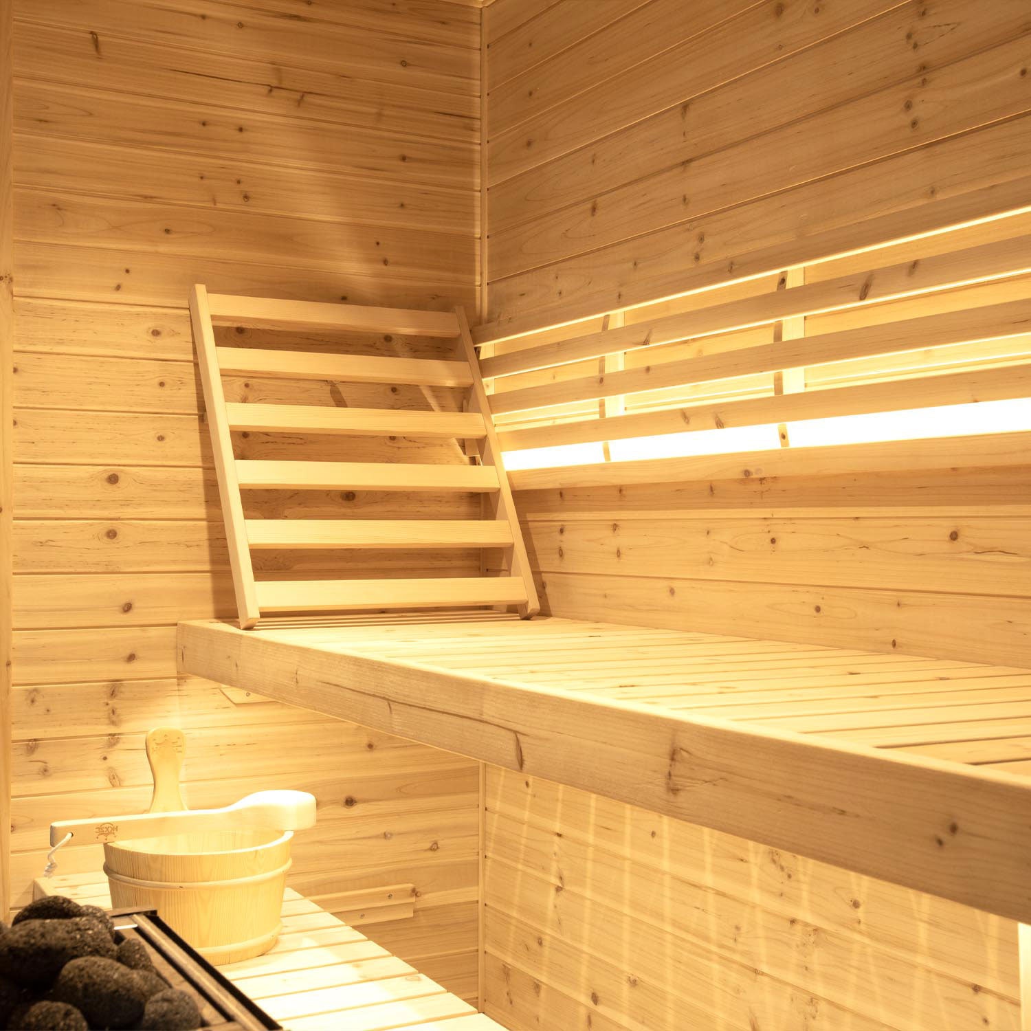 Outdoor triple sauna interior display contains backrest, wooden barrel and spoon
